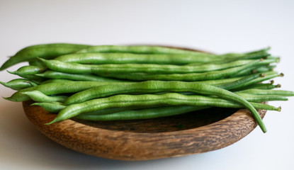 Phaseolus vulgaris or common bean on wooden plate. White background.