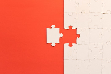 White jigsaw puzzles on red background. The concept of development of thinking. The concept of teamwork.