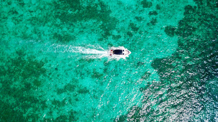 Fototapeta na wymiar Sports boat in the blue sea. The view from the drone. Expensive vacation. Yacht and turquoise, clear water. Transparent bottom of the water. Visible coral and cliff in the water. Travel to Asia.