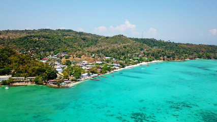 Fototapeta na wymiar Blue lagoon. Bay with clear sea. Green island with palm trees, Paradise. Drone footage. White sand on the beach. Lots of boats. You can see the ocean floor and sky. Travel in Asia, Phi, Thailand.