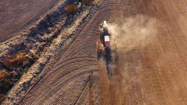 4K. Aerial view of agriculture process: tractor plows and makes seeding, sowing agricultural crops at field.
