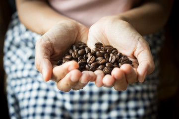Female holding coffee beans in hand.