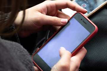 Close-up of a female hand with a mobile phone Smartphone in the hands of a girl. The thumb of the right hand is blurred in motion. Concept of work on modern mobilephone.
