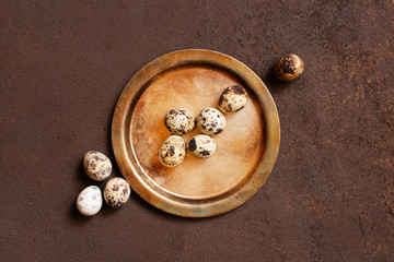 Small natural quail eggs on the vintage brass plate