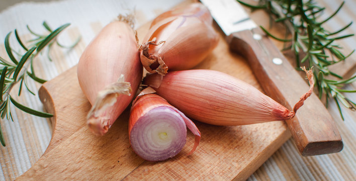 Close-up of shallots with fresh rosemary on cutting board