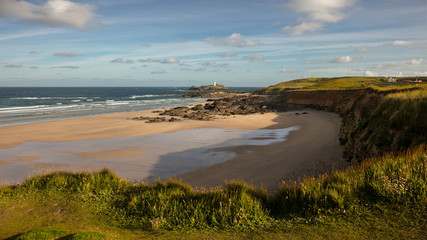 Eine schöne Bucht bei St. Ives und ein Leuchtturm auf einer kleinen Insel in Cornwall mit blauem Himmel und schönen Wolken
