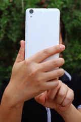 Asian woman holding and using smart phone show back side.