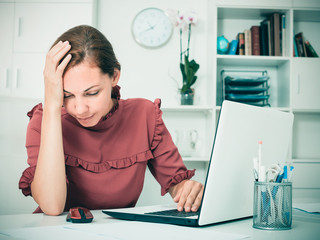 serious young woman sitting at working desk in company office