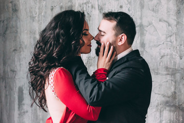 Portrait of the bride and groom. Red dress and black suit.
