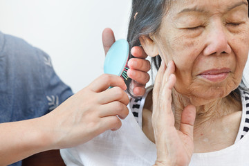 elderly woman combing hair by caregiver