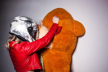 The concept of domestic violence. Sexy girl in a helmet is torturing a teddy bear