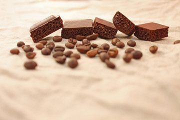 Chocolate cubes with coffee beans on a linen texture background.