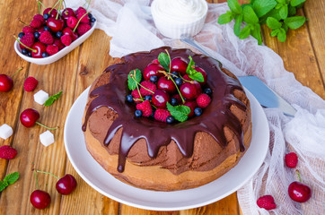Marble cream cake with chocolate glaze, fresh berries, whipped cream and mint.