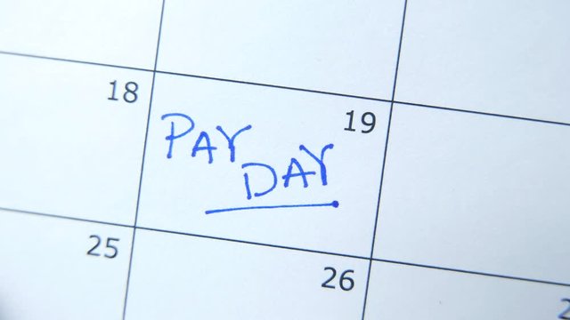Closeup on a calendar with PAY DAY being marked by a marker