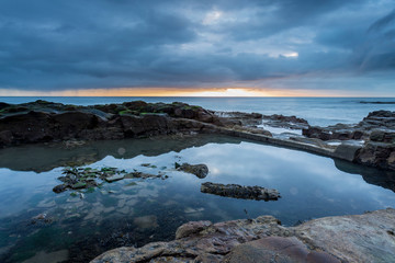 Fototapeta na wymiar Old and disused bathing pool at Table Rocks, Whitley Bay, on the north east coast of England at sunrise on an overcast day.