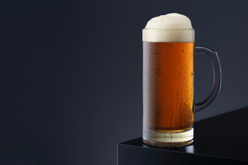 Mug of beer on black table and on dark grey background