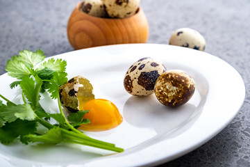 Broken quail eggs with parsley on the white table