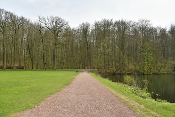 Fototapeta na wymiar Chemin en gravier rose longeant l'étang du Château au parc de Tervuren à l'est de Bruxelles 