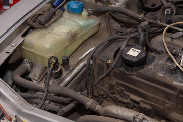 Diesel engine in the car and plastic water reservoir. Dirty old diesel engine.