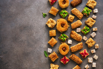 Various Eastern sweets on a rustic brown background. Baklava, delight, cookies. Top view, copy space.