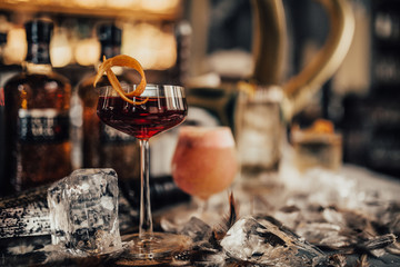 A close up shot of whisky cocktail in a martini glass with ice cubes and dry ice. Concept of fine alcohol, beverage and mixed cocktails. Luxurious lifestyle. Selective focus on the cocktails.