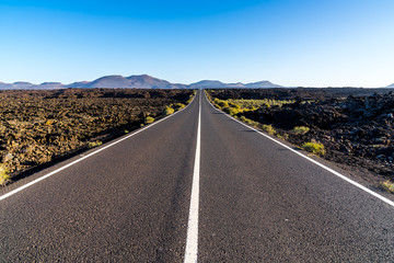 Spain, Lanzarote, Endless bolt upright asphalt road to magic red volcano mountains