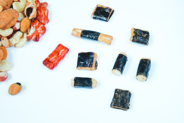 Mix of Asian snack on white background. Including Nori Maki Arare rice crackers in seaweed, glaze peanuts and fried crackers. Close up.