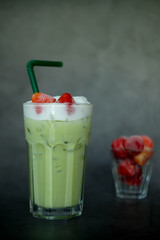 Close up milk froth green tea served with fresh strawberry
