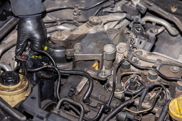 Car mechanic repairs diesel engine. Old and dirty car engine with car mechanics hands. Car repairing concept in the garage workshop.
