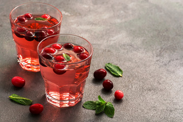 Cranberry juice in glasses with mint leaves on a dark table. Selective focus, place for text.