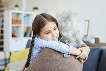 Portrait of cute little girl hugging grandma with love, copy space