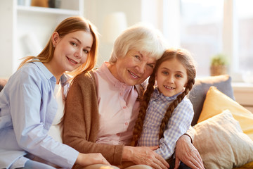Three generations of women, girl, mother and grandmother posing for family portrait in warm...