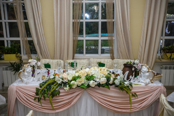 Fototapeta premium Wedding. Banquet. The chairs and round table for guests, served with cutlery, flowers and crockery and covered with a tablecloth
