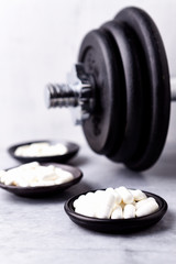 Creatine, Taurine, Beta Alanine capsules and a dumbbell. Bodybuilding food supplements on a stone...