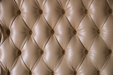 Beige leather detailed background with round buttons.
