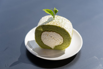 ​View of green tea cake roll put on top of wooden table.