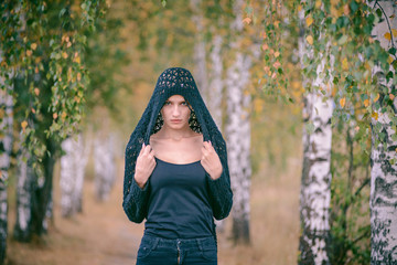 Attractive girl wearing a hood on her head walking in the Park.