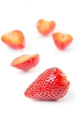 Red fresh cut and whole strawberries arranged on a white background.