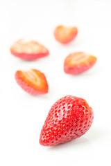 Red fresh cut and whole strawberries arranged on a white background