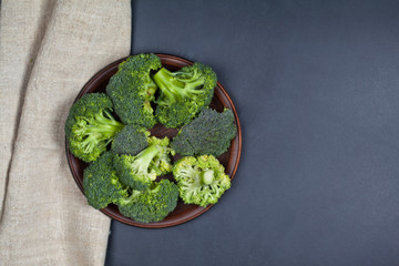 Fresh green organic broccoli in brown plate and linen napkin.