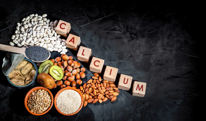 Foods rich in calcium such as sardines, bean, almonds, hazelnuts on dark background