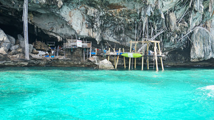Sheer cliffs, blue water and a Viking cave. Phi Phi Islands, Thailand. See the stalactites, and built of bamboo. The turquoise colour of the water. Unusual landscape. The stones of the deserted island