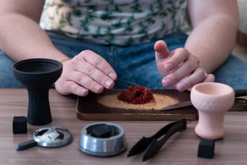Hookah in the process preparations. The bartender grinds tobacco.