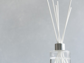Aromatizer. Aromatic air freshener in a transparent glass bottle with white reeds on a gray...