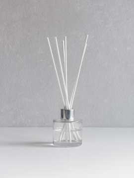 Aromatizer. Aromatic air freshener in a transparent glass bottle with white reeds on a gray background
