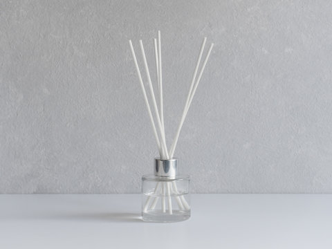Aromatizer. Aromatic air freshener in a transparent glass bottle with white reeds on a gray background