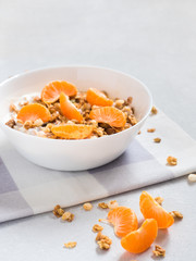 Healthy breakfast. Baked muesli with tropical fruits, fresh tangerines and yogurt on white background