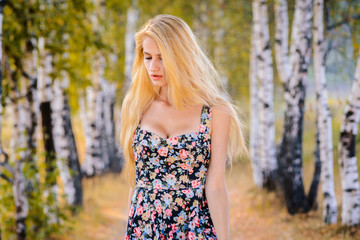 An attractive girl with long hair in a short dress walks in the Park.