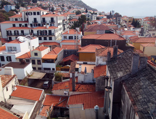 an aerial view of funchal in madeira showing red tiled roofs of old white buildings with the coast...