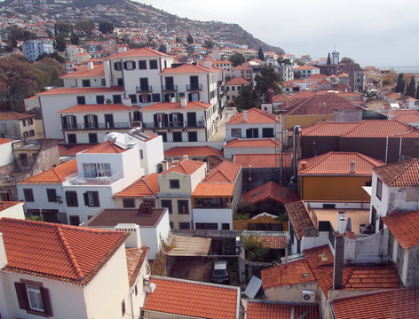 an aerial view of funchal in madeira showing red tiled roofs of old white buildings with the coast in the distance